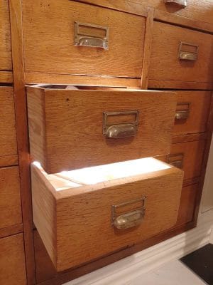 Avoin puinen laatikko, jossa on lämmin LED-valo, kontrastivärinen ruskea puusyiden lipasto; metallikahvat korostavat modernia eleganssia valaistusratkaisuissa.