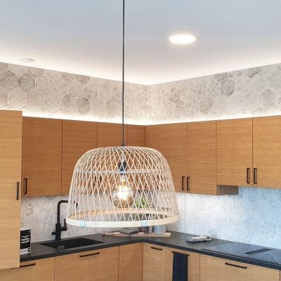 Asuntomessut 2020: Epäsuorat valot keittiön kaapistossa päällä tammikeittiössä. Plafondit katossa ja ruokapöyän päällä riippuvalaisin. Ledstore.fi