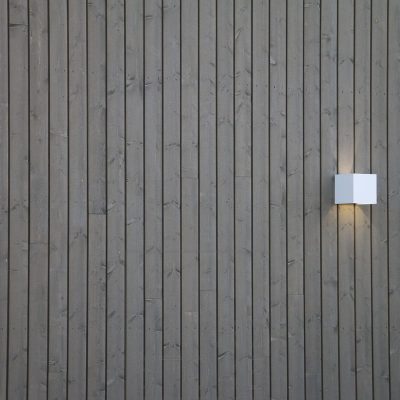 Valkoinen FUNK seinävalaisin ulkona valaisemassa julkisivua sekä luomassa tunnelmallista, epäsuoraa valaistusta ulos. Ledstore.fi  