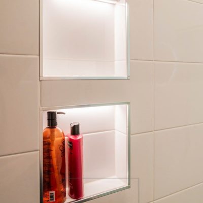 Kylpyhuoneessa pienissä shampoohyllyissä led nauhat valaisemassa ja korostamassa syvennyksiä. Ledstore.fi