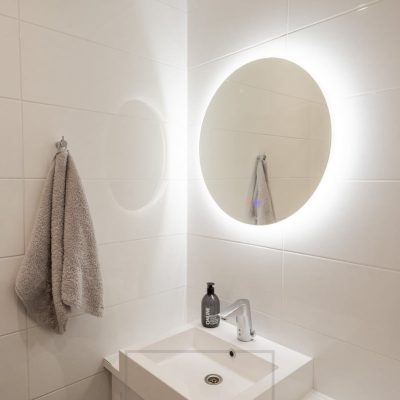 Pyöreä valopeili valaisemassa kylpyhuonetta. Valopeili valaisee seinän kautta ja lisäksi tilassa spotti valaisemassa suoraan alas. Ledstore.fi