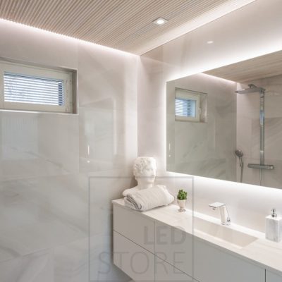 Kylpylämäisessä kylpyhuoneessa iso, tilaa avartava valopeili yhdistettynä spottivaloihin sekä seinän ja katon väliin asennettuun led nauhaan.