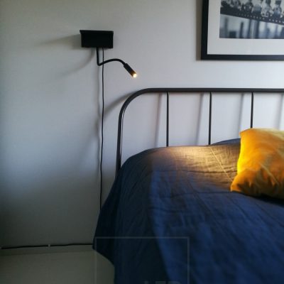 Sängyn vieressä BLADE seinävalaisin. Toimii lukuvalona  ja valaisimessa on sekä kiinteä että langaton lataus puhelinta varten. Ledstore.fi