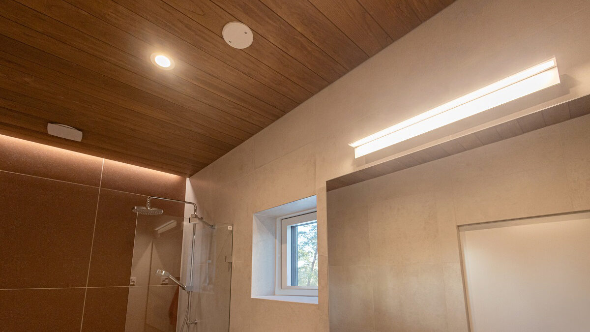 Moderni kylpyhuone, jossa puukatot, beiget seinät, suihku ja ikkuna. Kirkas LED-yleisvalaistus LedStore.fi:ltä. - LedStore Moderni kylpyhuone, jossa on puinen katto, uppoasennetut LED-valot ja suuri lasiseinäinen suihku. Sileään beigeen laattaseinään on upotettu pieni ikkuna luontonäkymällä, ja sen vieressä on suorakulmion muotoinen LED-valaisin. Tämä kuvaus sopiilaadukasta.sti LedStorefi-verkkokauppaan, joka tarjoaa LED-valaistusta kodin kaikkiin tiloihin.