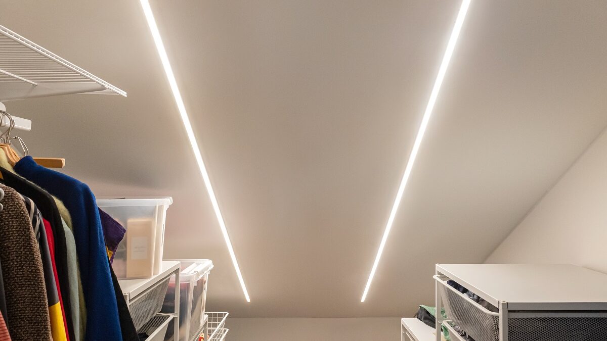Vaatehuoneen katossa kaksi kirkasta LED-listaa LedStore.fi:ltä, valaisten vaatteet ja säilytyslaatikot molemmin puolin. - LedStore Vinokattoinen siististi koulutus vaatekaappi, jossa on kaksi LED-valaisinta LedStore.fi verkkokaupasta. Vaatteet roikkuvat vasemmalla puolella, kun taas säilytyslaatikot ja hyllyt sijaitsevat molemmilla puolilla. LED-valaistus huomio modernia ja selkeää tunnelmaa.