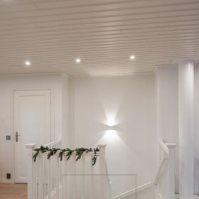Valkoinen led seinävalaisin FUNK valaisemassa portaikkoa, yleisvalaistuksena tilassa pyöreät 9W spotit katossa. Ledstore.fi