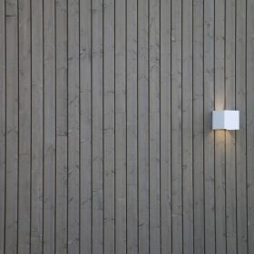 Valkoinen FUNK seinävalaisin ulkona valaisemassa julkisivua sekä luomassa tunnelmallista, epäsuoraa valaistusta ulos. Ledstore.fi