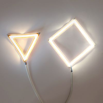 Kaksi LED-neonseinävalaisinta, kolmion ja timantin muotoiset, valkoisilla kaapeleilla, moderni koristeellinen valaistus.