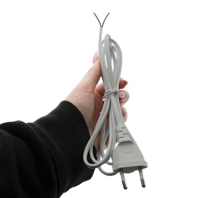 Kädessä pidettävä LED-valaisimen virtajohto, esillä johtimet, valkoinen tausta, sähkötarvike.