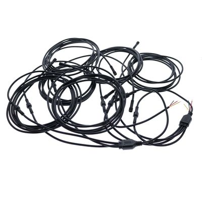 Mustat LED-valokaapelit, joissa on liittimet ja näkyvät johdot, käärittyinä ja sotkeutuneina valkoisella pohjalla.