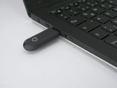 USB-muistitikku kytketty kannettavaan tietokoneeseen valkoisella pohjalla, symboloi liitettävyyttä ja teknologiaa moderneissa LED-valaistusratkaisuissa.