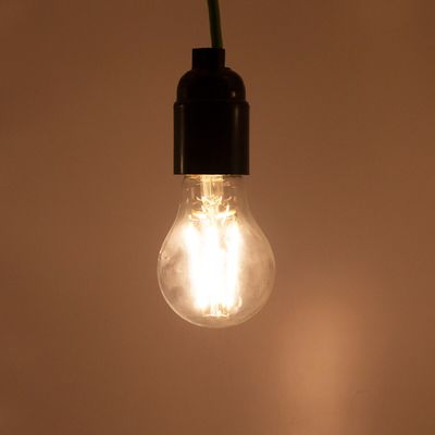 Johdosta riippuva LED-lamppu säteilee pehmeää hehkua neutraalia taustaa vasten esitellen moderneja energiatehokkaita valaistusratkaisuja.