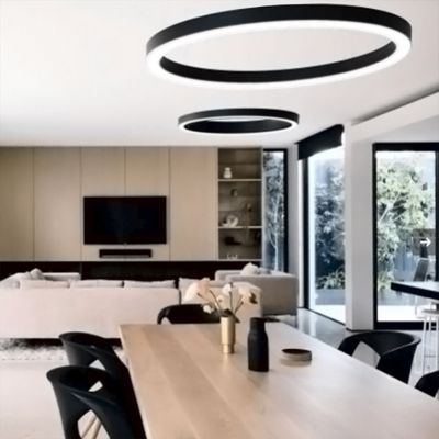 Modernit LED-kattovalot valaisevat avaraa oleskelu-/ruokailutilaa, jossa on puupöytä, beige sohva, tv seinällä, suuret ikkunat ja minimalistinen sisustus.