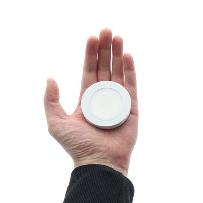 Kädessä energiatehokas, pienikokoinen LED-lamppu ympäristöystävällisiin valaistusratkaisuihin valkoista taustaa vasten. Täydellinen moderniin kodin valaistukseen.