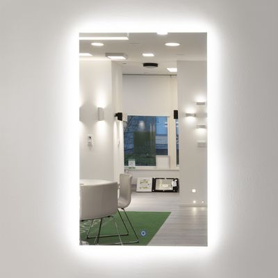 Valaistu peili, joka heijastaa modernia sisustusta, jossa riippuvalaisimet, tyylikkäät tuolit ja luonnonvalo.