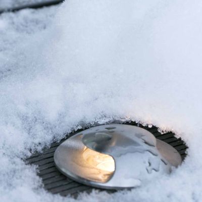 Lumiseen maisemaan upotettu ulkokäyttöinen LED-maavalo, joka valaisee pehmeästi polkuja, puutarhoja ja ulkotiloja.