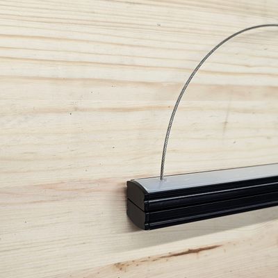 Lähikuva mustasta kehyksestä lankaripustimella vaalealla puupinnalla, ihanteellinen moderniin LED-valaistusnäyttöön kodin sisustuksessa ja suunnittelussa.