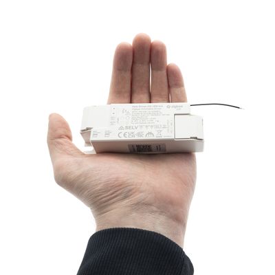 Henkilö pitelee LED-valokaukosäädintä, joka näyttää kokoa ja toimintoja ja esittelee modernia valaistustekniikkaa myymälässä.