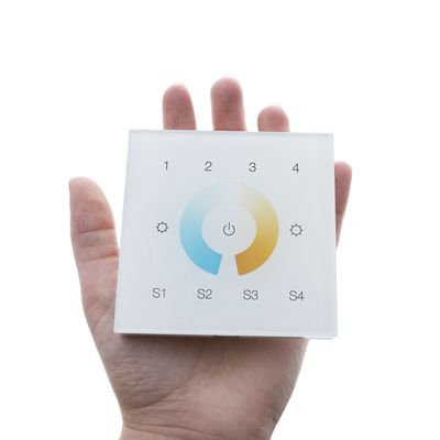 Vaihtoehtoinen teksti: "Pidä kädellä nelikulmaista lasikosketuspaneelia LED-valaistuksen ohjaamiseen virtalähteellä, asetuskuvakkeilla, väripyörällä ja S1-S4-painikkeilla.