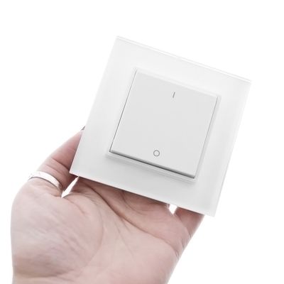 Kädessä tyylikäs, minimalistinen valkoinen nelikulmainen valokytkin LED-valaistusliikkeestä moderniin sisustukseen.