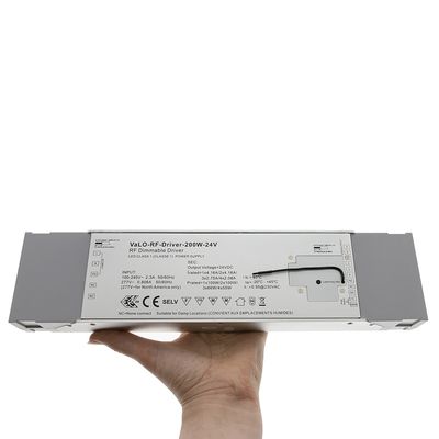 Käsi kädessä harmaata VaLO-RF Driver-200W-24V, joka näyttää tulo-/lähtötiedot ja LED-valaistusjärjestelmien turvakuvakkeet.