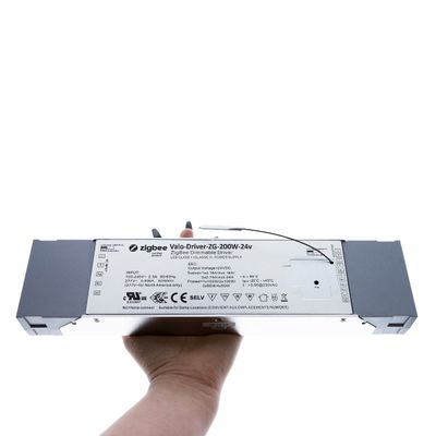 Kädessä on suorakaiteen muotoinen Zigbee Varo-Driver ZG-200W-24v, jossa on näkyviä tarroja, mikä parantaa älykästä valaistusliitettävyyttä LED-asennuksissa.