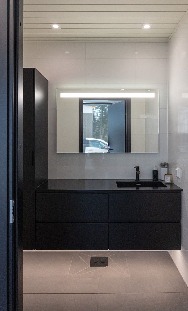 Kylpyhuoneessa led nauha kaappien alla antamassa epäsuoraa valoa, SEELIA peilivalaisin sekä katossa kaksi SQ023 LED alasvaloa.