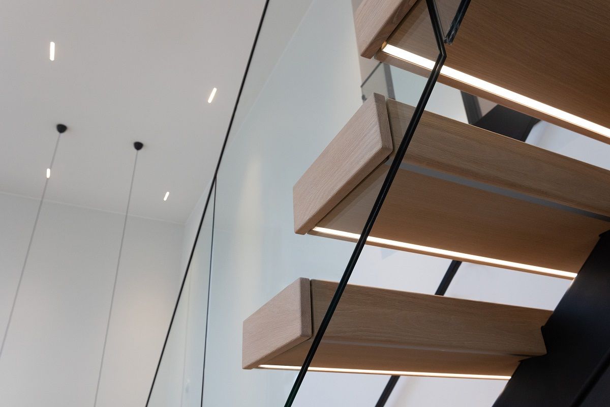 Porrasaskelman alle, etureunaan uppoasennettuna led nauhaa profiilissa. Taustalla katossa LINJA10 led spotit.