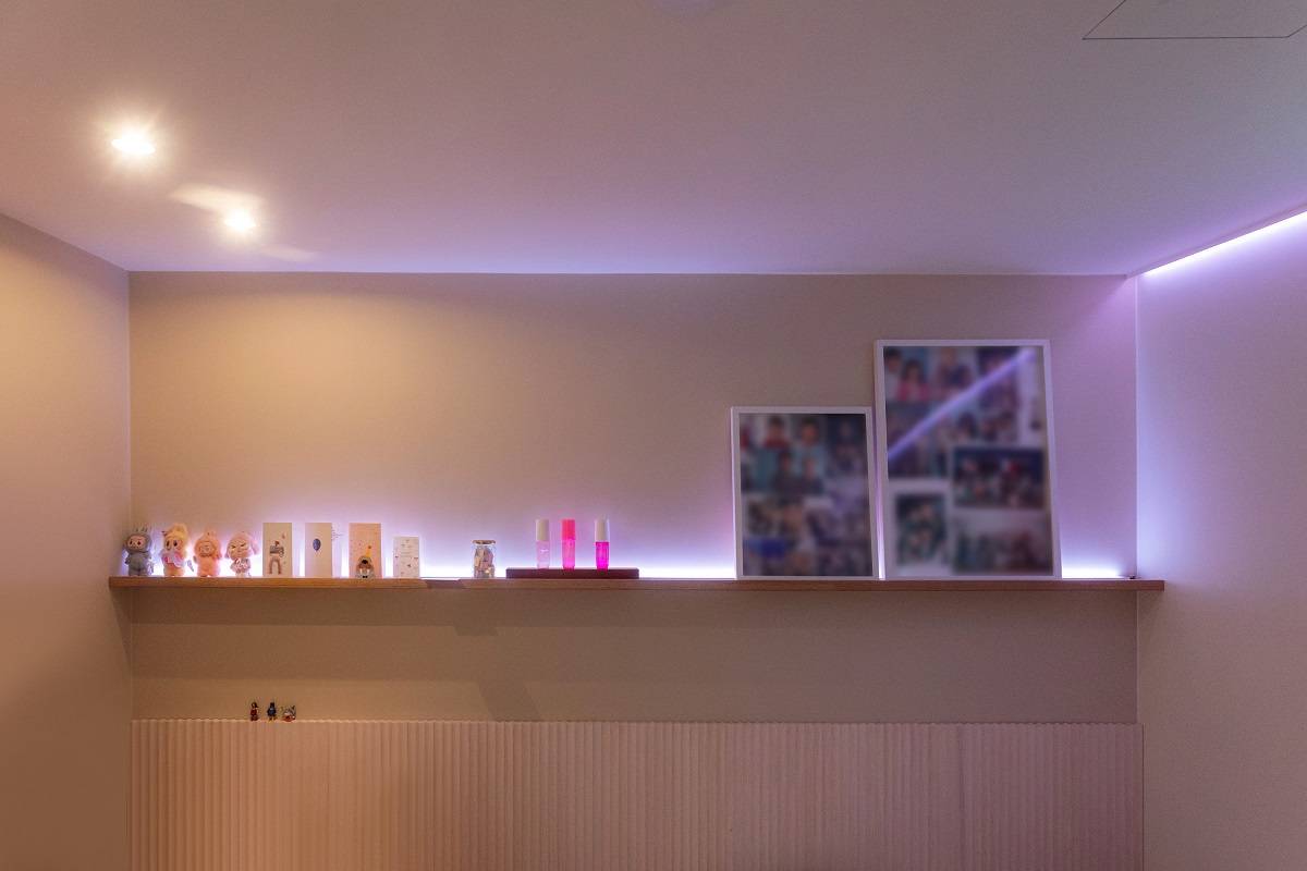 Lilaa valoa tuova LED nauha kiertää huonetta, katossa lisäksi kaksi spottivalaisinta.