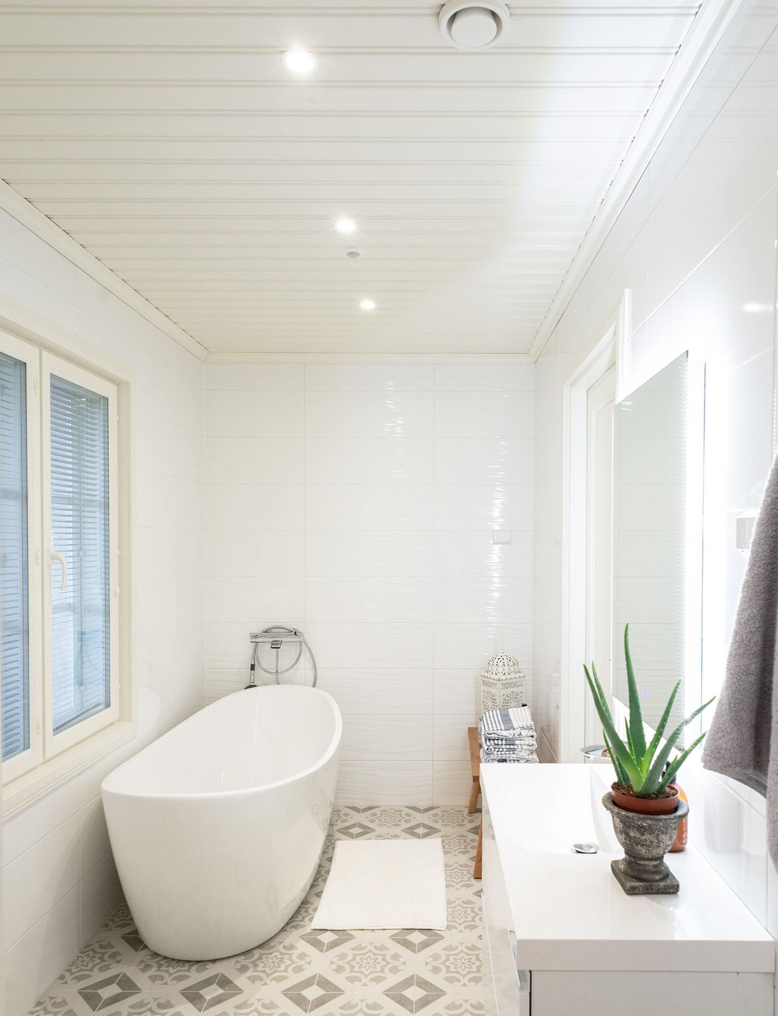 Spottivalaisimet kylpyhuoneen katossa ja valopeili valaisemassa pesualtaalla.