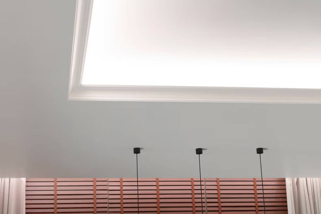 Toimiva valaistuskokonaisuus olohuoneessa. Katon valohyllyllä oleva led-nauhavalaistus valaisee kohti kattoa ja alaspäin kohti verhoja.