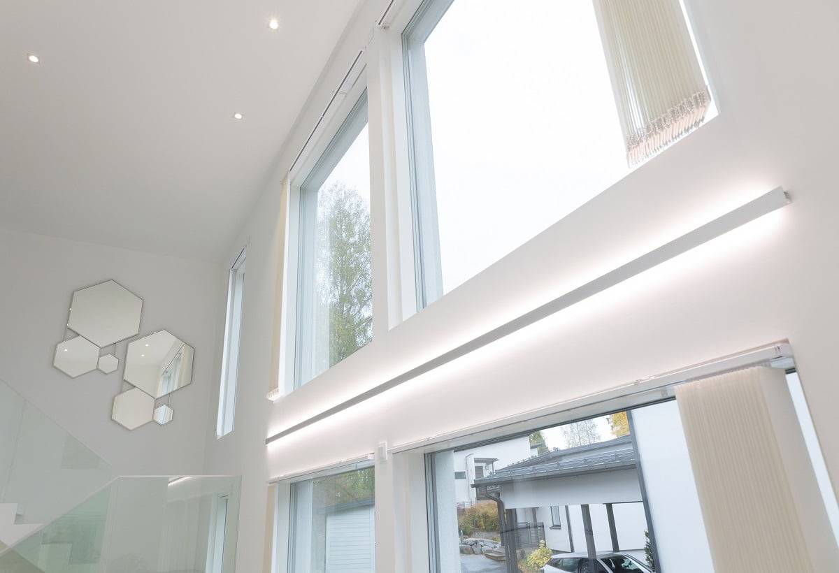 LedStore.fi-verkkokaupan tuotekuvaus: Modernissa sisustuksessa on upeat suuret ja korkeat ikkunat, ongelmat tyylikäs LED-valaistus. Tämä valaistus mahdollistaa luonnonvalon upean tulvimisen sisään. Valkoisilla seinillä on taiteellisesti aseteltu joukko kuusikulmaisia peilejä portaikon lähellä, jonka kaide on lasia. Ulkona ajotieltä löytyy pysäköityjä autoja, jotka täydentävät modernin tyylin kokonaisuutta.