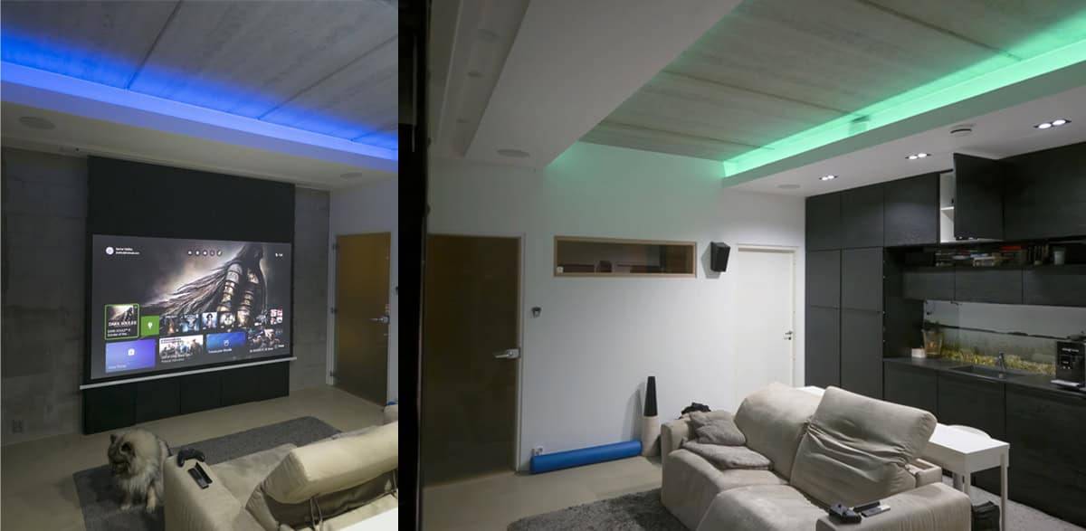Moderni olohuone, jossa LedStore.fi LED-valaistus kotiteatteria varten, projektorinäyttö, mukavat istuimet ja koira lattialla.